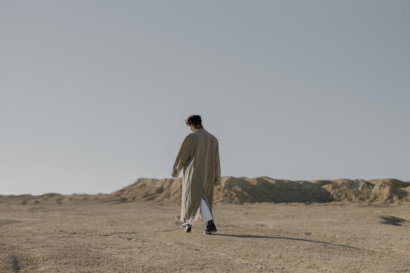 Man in White Thobe Walking on Brown Sand